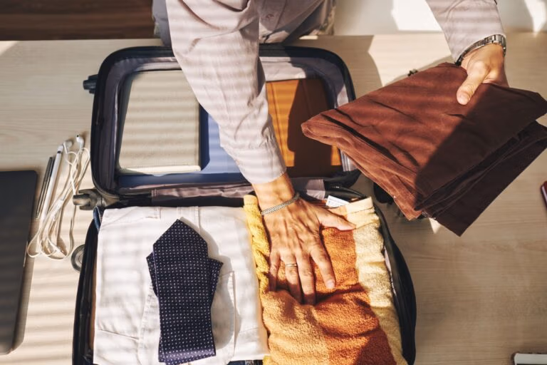 Ein Mann packt seinen Koffer für eine Geschäftsreise auf einen Bett.